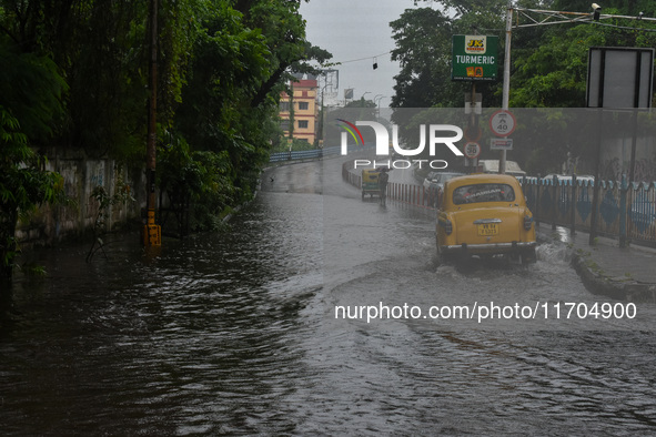 Motorists make their way through a flooded road after Cyclone Dana thrashes the city with heavy rain, as seen in Kolkata, India, on October...