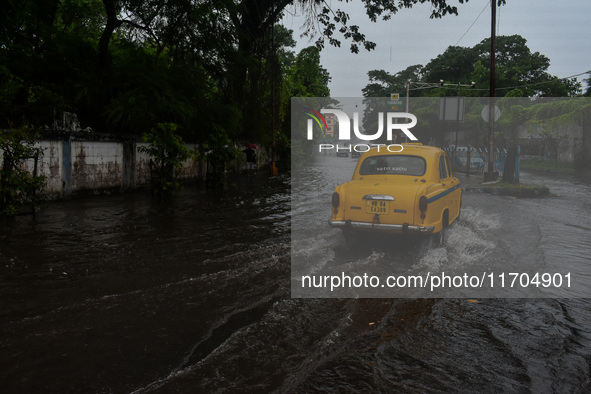 Motorists make their way through a flooded road after Cyclone Dana thrashes the city with heavy rain, as seen in Kolkata, India, on October...