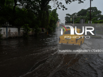 Motorists make their way through a flooded road after Cyclone Dana thrashes the city with heavy rain, as seen in Kolkata, India, on October...