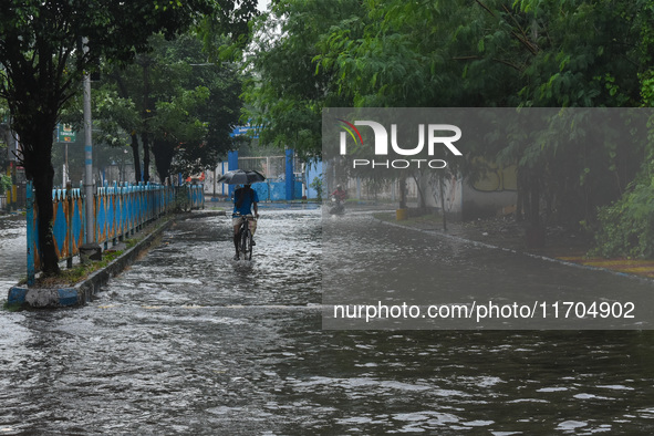 Motorists make their way through a flooded road after Cyclone Dana thrashes the city with heavy rain, as seen in Kolkata, India, on October...