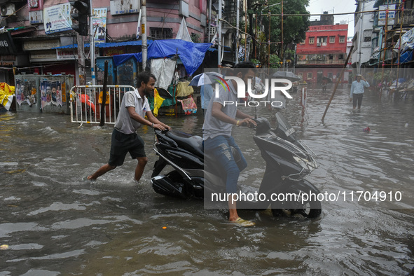 A man pushes a scooter through a flooded road in Kolkata, India, on October 25, 2024. Cyclone Dana makes landfall on the coast of Odisha and...