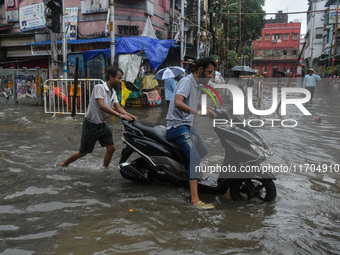 A man pushes a scooter through a flooded road in Kolkata, India, on October 25, 2024. Cyclone Dana makes landfall on the coast of Odisha and...