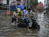 A man pushes a scooter through a flooded road in Kolkata, India, on October 25, 2024. Cyclone Dana makes landfall on the coast of Odisha and...