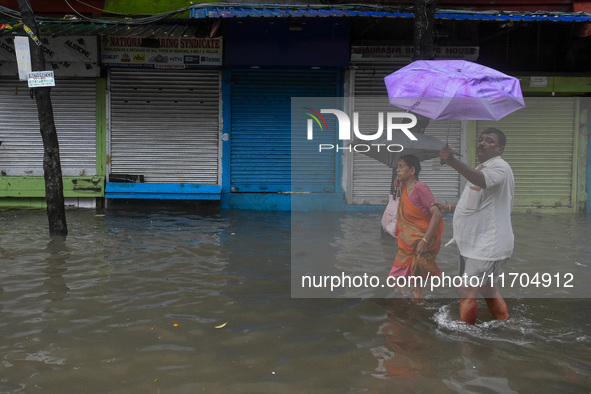 People are seen on a flooded road in Kolkata, India, on October 25, 2024, after heavy rain brought by the landfall of Cyclone Dana. Cyclone...