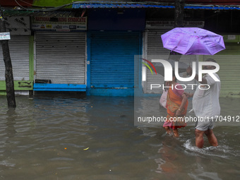 People are seen on a flooded road in Kolkata, India, on October 25, 2024, after heavy rain brought by the landfall of Cyclone Dana. Cyclone...