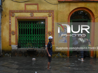 A father carries his son on his lap through a flooded road in Kolkata, India, on October 25, 2024, after heavy rain brought by the landfall...