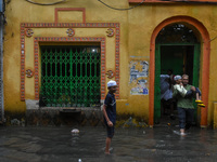 A father carries his son on his lap through a flooded road in Kolkata, India, on October 25, 2024, after heavy rain brought by the landfall...