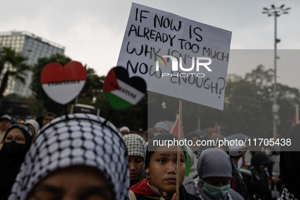 A protester holds a placard during a rally in solidarity with the Palestinian people outside the US embassy in Jakarta, Indonesia, on Octobe...