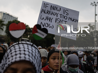 A protester holds a placard during a rally in solidarity with the Palestinian people outside the US embassy in Jakarta, Indonesia, on Octobe...