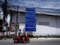 A motorcyclist rides past signs pointing to Tak Bai areas beneath clusters of electric wires. Daily life in Tak Bai, Narathiwat, Thailand, o...