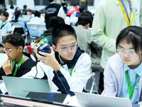 Participants program a robot during the Qingdao International Invitational Tournament of the 2024 Asia-Pacific RoboCup in Qingdao, China, on...