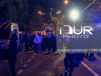 Residents watch as emergency services fight a fire after a Russian drone hits a residential high-rise in Kyiv, Ukraine, on October 25, 2024....