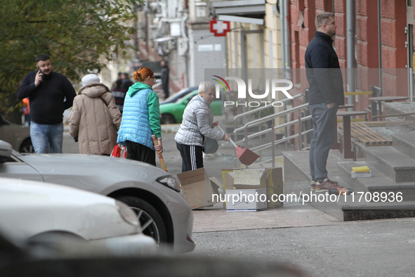 Women sweep away grass shards outside a shop after a Russian strike in Dnipro, Ukraine, on October 26, 2024. NO USE RUSSIA. NO USE BELARUS. 