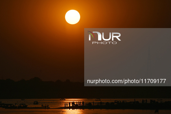 Visitors are silhouetted against the setting sun as they ride a boat during sunset at Sangam, the confluence of the rivers Ganges, Yamuna, a...