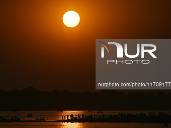 Visitors are silhouetted against the setting sun as they ride a boat during sunset at Sangam, the confluence of the rivers Ganges, Yamuna, a...