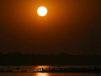 Visitors are silhouetted against the setting sun as they ride a boat during sunset at Sangam, the confluence of the rivers Ganges, Yamuna, a...