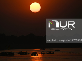 Visitors are silhouetted against the setting sun as they ride a boat during sunset at Sangam, the confluence of the rivers Ganges, Yamuna, a...