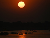 Visitors are silhouetted against the setting sun as they ride a boat during sunset at Sangam, the confluence of the rivers Ganges, Yamuna, a...