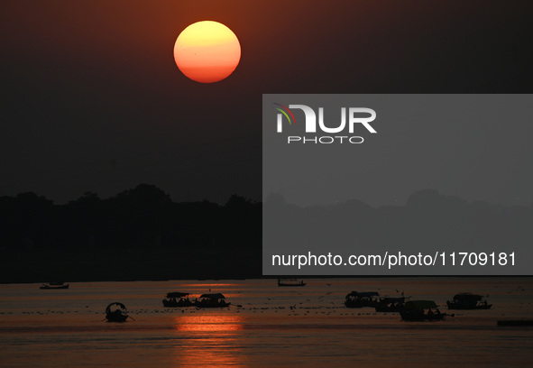 Visitors are silhouetted against the setting sun as they ride a boat during sunset at Sangam, the confluence of the rivers Ganges, Yamuna, a...