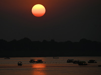 Visitors are silhouetted against the setting sun as they ride a boat during sunset at Sangam, the confluence of the rivers Ganges, Yamuna, a...