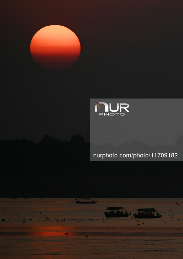 Visitors are silhouetted against the setting sun as they ride a boat during sunset at Sangam, the confluence of the rivers Ganges, Yamuna, a...