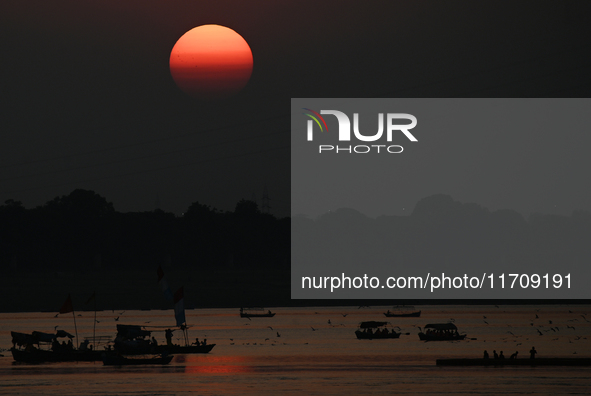 Visitors are silhouetted against the setting sun as they ride a boat during sunset at Sangam, the confluence of the rivers Ganges, Yamuna, a...