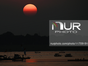 Visitors are silhouetted against the setting sun as they ride a boat during sunset at Sangam, the confluence of the rivers Ganges, Yamuna, a...