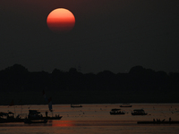 Visitors are silhouetted against the setting sun as they ride a boat during sunset at Sangam, the confluence of the rivers Ganges, Yamuna, a...