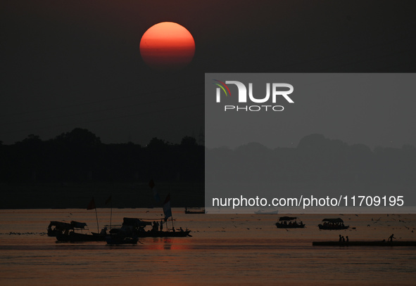 Visitors are silhouetted against the setting sun as they ride a boat during sunset at Sangam, the confluence of the rivers Ganges, Yamuna, a...