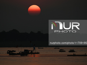 Visitors are silhouetted against the setting sun as they ride a boat during sunset at Sangam, the confluence of the rivers Ganges, Yamuna, a...