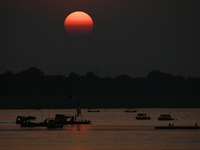 Visitors are silhouetted against the setting sun as they ride a boat during sunset at Sangam, the confluence of the rivers Ganges, Yamuna, a...