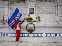 In Lisbon, Portugal, on October 26, 2024, a person holds a flag from Cabo Verde at an improvised memorial at Praca dos Restauradores. They p...