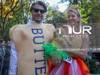 A couple and their dog dress as popcorn and butter for the Washington Square Park Halloween Dog Parade in New York, N.Y., on October 26, 202...