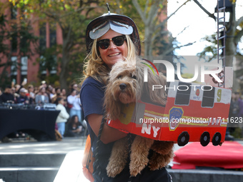 A woman dresses as a firefighter and carries her dog, which is dressed as a fire truck, during the Washington Square Park Halloween Dog Para...