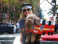 A woman dresses as a firefighter and carries her dog, which is dressed as a fire truck, during the Washington Square Park Halloween Dog Para...