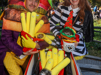 A couple dresses as McDonald's characters with a cart filled with Pomeranians dressed as hamburgers and french fries and poses for a photo d...