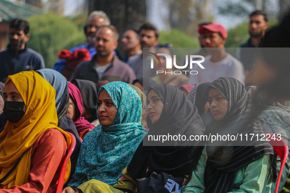 An Indian policeman stands guard as Kashmiri girls look on during the traditional women's boat race in Srinagar, Jammu and Kashmir, on Octob...