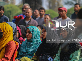 An Indian policeman stands guard as Kashmiri girls look on during the traditional women's boat race in Srinagar, Jammu and Kashmir, on Octob...