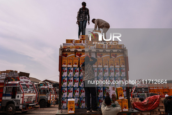 Workers load apple boxes onto trucks, which are sent to different parts of the country from Asia's largest fruit market in Sopore, Jammu and...