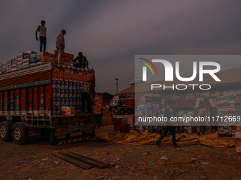 Workers load apple boxes onto trucks, which are sent to different parts of the country from Asia's largest fruit market in Sopore, Jammu and...