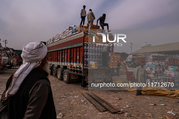 Workers load apple boxes onto trucks, which are sent to different parts of the country from Asia's largest fruit market in Sopore, Jammu and...