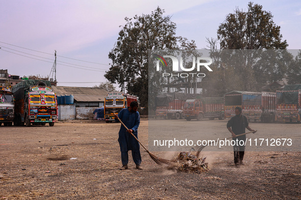 Workers use a broom to clean the trash from the apple market in Sopore, Jammu and Kashmir, India, on October 27, 2024. 