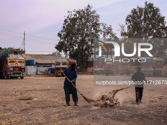 Workers use a broom to clean the trash from the apple market in Sopore, Jammu and Kashmir, India, on October 27, 2024. (