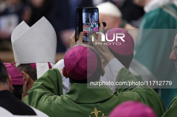 A priest takes a picture during Pope Francis's Mass for the closing of the 16th General Assembly of the Synod of Bishops in St. Peter's Basi...