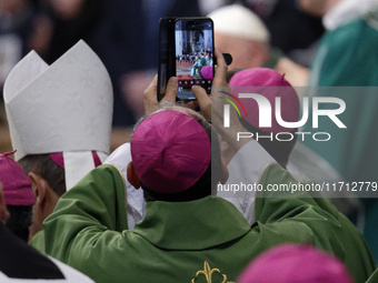 A priest takes a picture during Pope Francis's Mass for the closing of the 16th General Assembly of the Synod of Bishops in St. Peter's Basi...