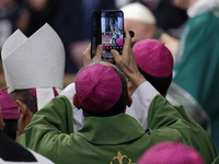 A priest takes a picture during Pope Francis's Mass for the closing of the 16th General Assembly of the Synod of Bishops in St. Peter's Basi...