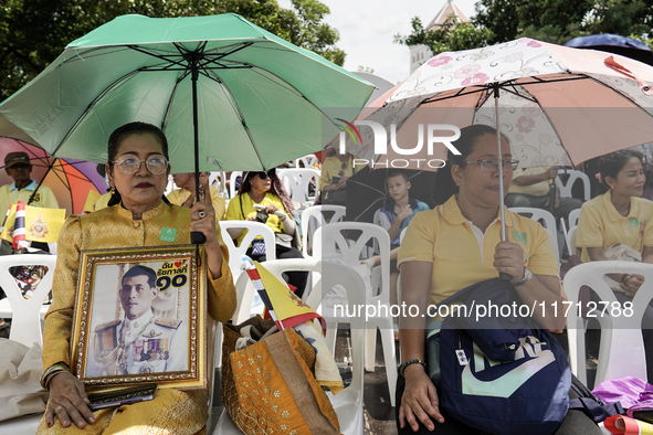 Thai royalist supporters hold portraits of Thai King Maha Vajiralongkorn as they wait for the Royal Barge Procession for the Royal Kathin ce...