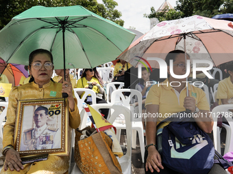 Thai royalist supporters hold portraits of Thai King Maha Vajiralongkorn as they wait for the Royal Barge Procession for the Royal Kathin ce...