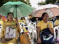 Thai royalist supporters hold portraits of Thai King Maha Vajiralongkorn as they wait for the Royal Barge Procession for the Royal Kathin ce...