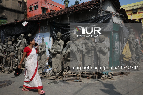 A woman speaks on her mobile phone as she walks past semi-finished clay idols of the Hindu mythological characters ''Dakinis'' and ''Yoginis...